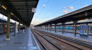 Quai de gare avec plusieurs voies ferrées qui s'éloignent sous un ciel bleu