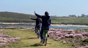eux cyclistes de dos sur un chemin fleuri au bord de la mer