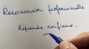 Main écrivant « Reconversion professionnelle, reprendre confiance » au feutre bleu